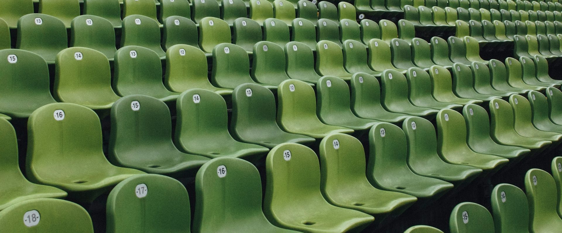 Reihen von grünen Stadion- oder Tribünensitzen.